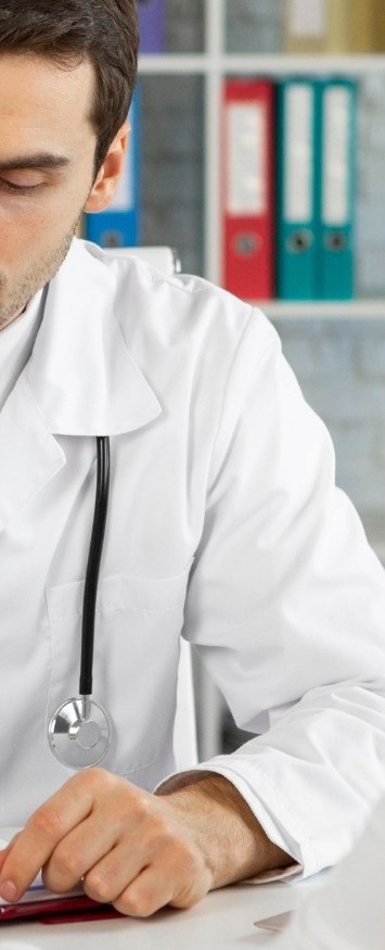 A clinician in a white coat and stethoscope at a desk